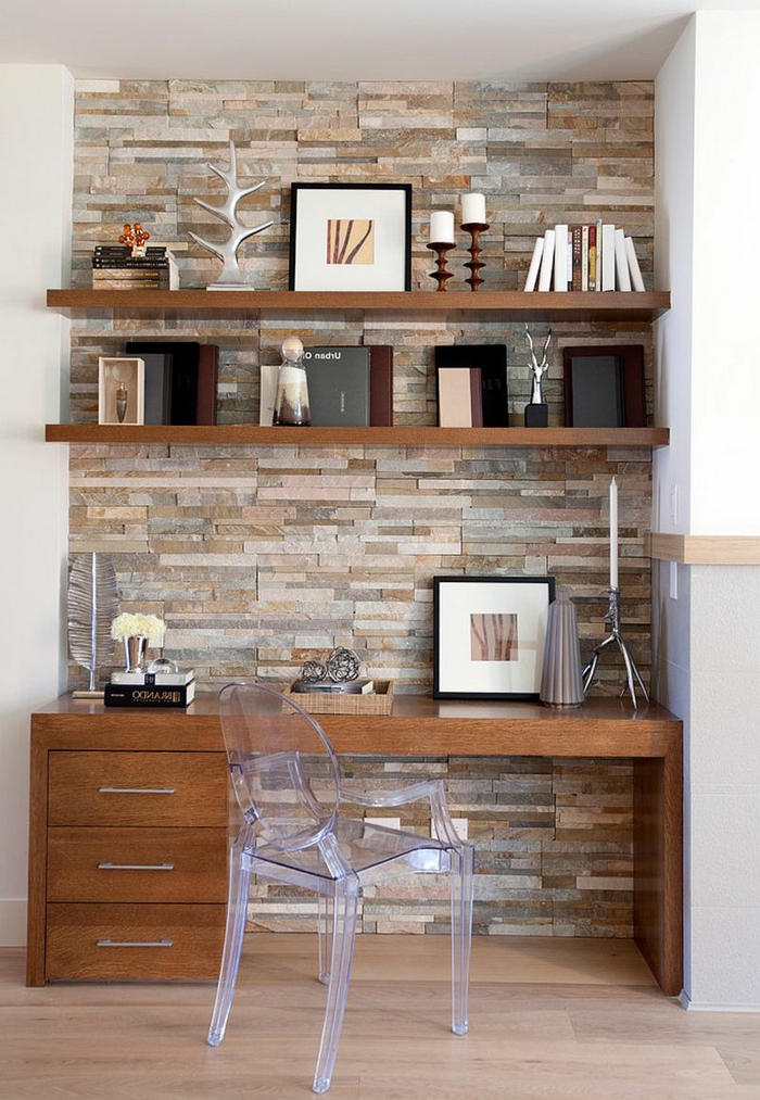 ladrillo visto, escritorio de madera con silla transparente, pared de piedra decorativa y estantes con libros