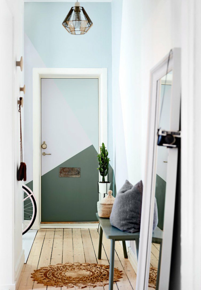muebles de entrada, recibidor en el pasillo, suelo de tarima con tapete redondo, espejo apoyado en el suelo, paredes en azul y verde