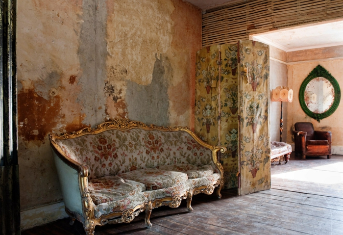 vintage, salón vintage, paredes con efecto muy desgastado, grande sofá con bordes dorados tapizada con estampado de motivos florales