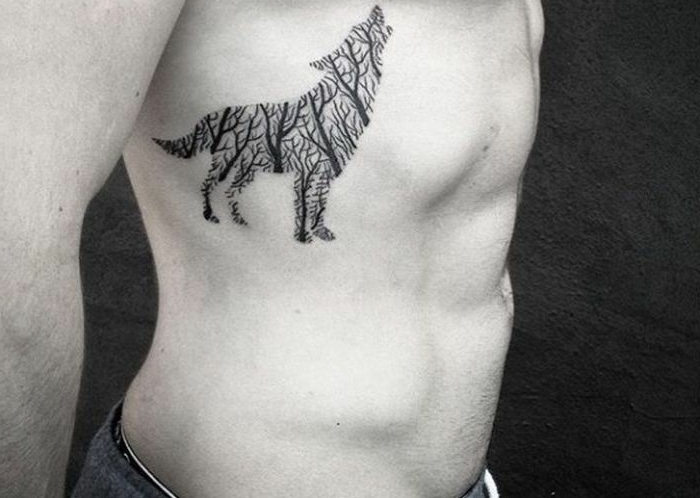 tatuaje lobo, hombre con tatuaje en el torzo, lobo aullando con cuerpo hecho de ramas de árboles sin hojas