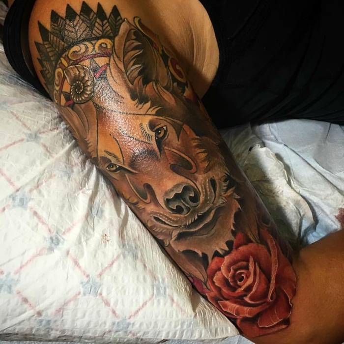 mejores tatuajes, tatuaje en el brazo con cabeza de lobo, corona de plumas indiana y rosa, estilo neoclasico, tatuaje de colores
