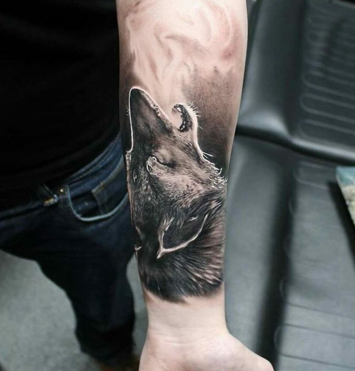 tatuajes de animales, tatuaje negro masculino en el antebrazo, cabeza de lobo en estilo realista, hombre en jeans