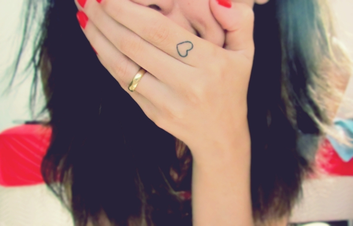 tatuajes en la mano, mujer con uñas rojas, pelo largo y anillo de boda, tatuaje de corazón pequeño en el índice