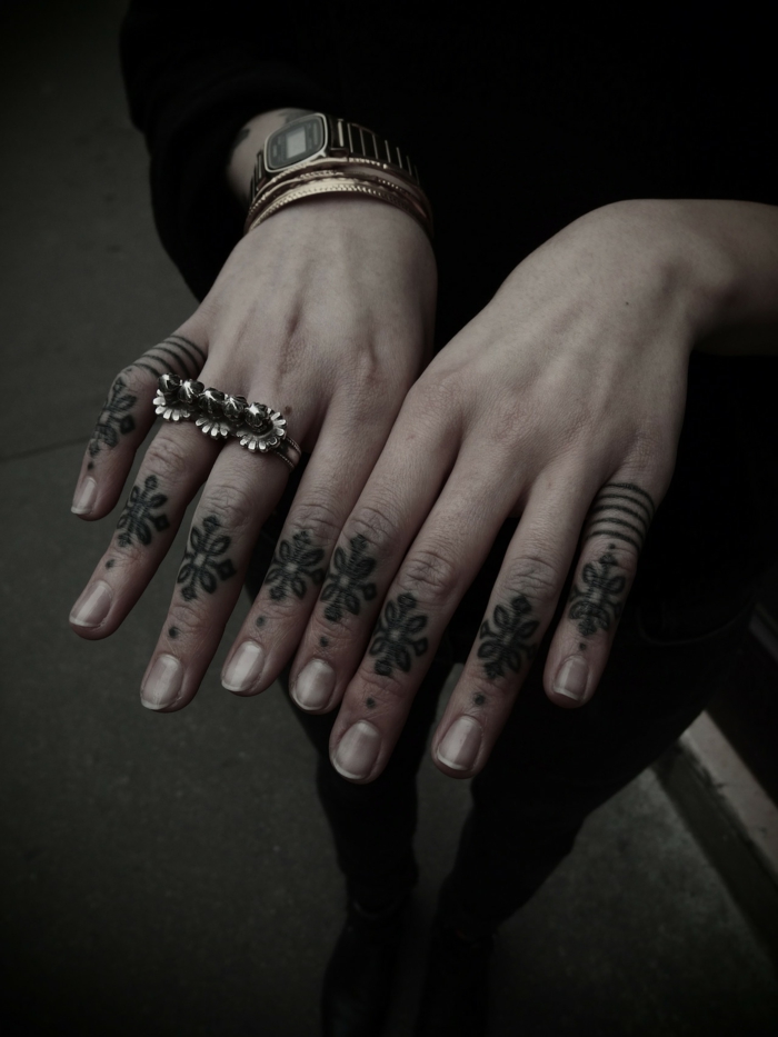 tatuajes en la mano, mujer con manicura francesa, anillos y reloj, dedos tatuados con flores y tatuaje de anillo
