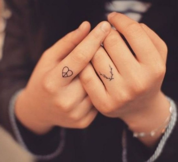 tatuajes dedos, manos de mujer con pulsera, tatuajes minimalistas, el símbolo de la paz en corazón y laurel