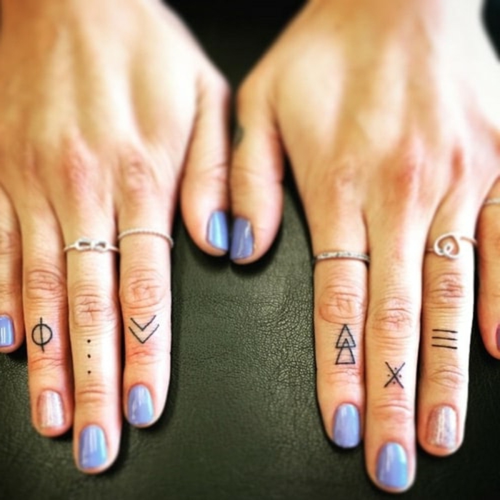 tatuaje corazon, manos de mujer con uñas de color y anillos, tatuajes minimalista con figuras geométricas en los dedos
