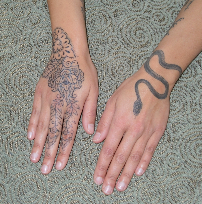 tatuajes mujer, manos de mujer con tatuajes diferentes, mano izquierda con serpiente, mano derecha con motivos florales en la mano y los dedos