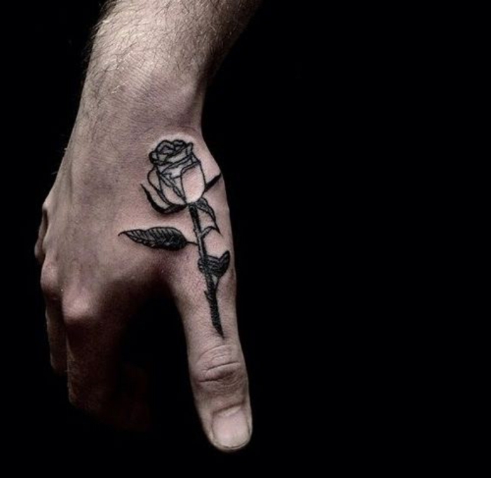 ideas para tatuajes, tatuaje grande en la muñeca y el pulgar, rosa con hojas en negro, mano de hombre