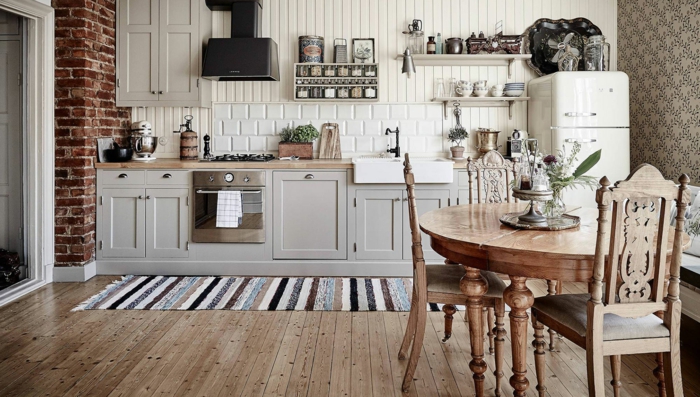 habitacion vintage, cocina con paredes de ladrillos, suelo de parquet, mesa oval y sillas de madera vintage
