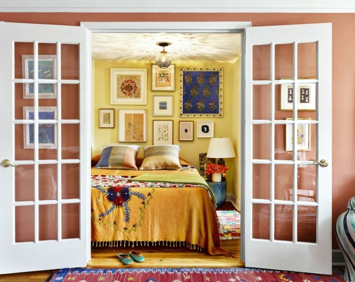 interior en estilo vintage, dormitorio acogedor con puerta original de madera, paredes en amarillo y salmón, cuadros para dormitorios matrimonio 