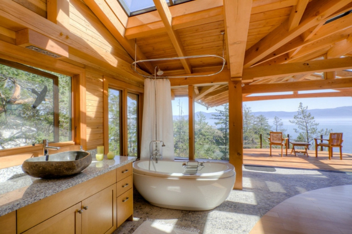 baño rústico con bañera oval moderna, lavabo típico para los baños rusticos, techo de madera y suelo de mármol 