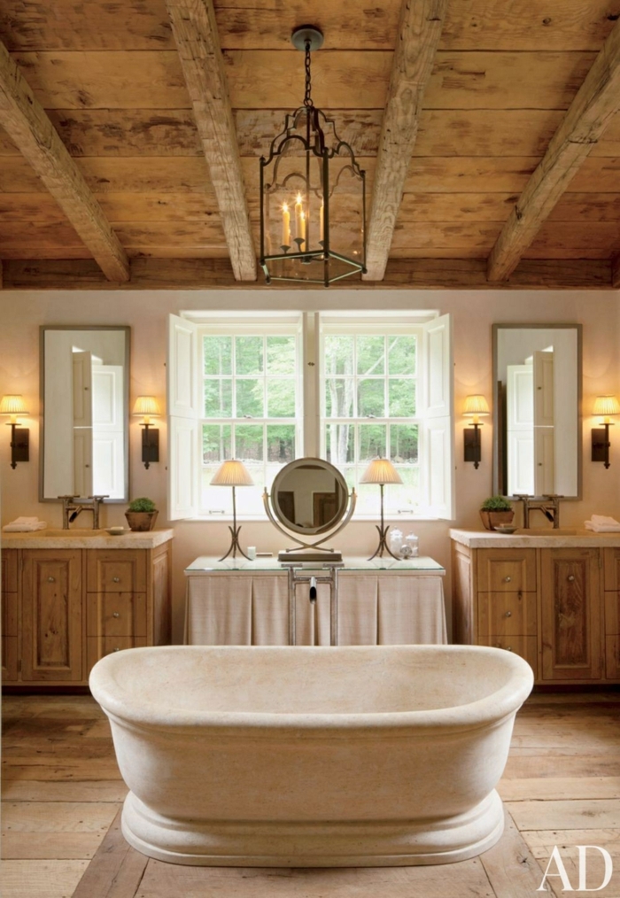 baños rusticos con aire cálido y acogedor, revestimiento de madera y bañera exenta, techo con vigas de madera y lámpara vintage