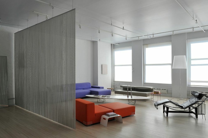 separadores de ambientes, espacioso salón en gris con enfoque en el sofá de color lila y en en sillón en anaranjado, suelo de parquet y separador de ambientes refinado 