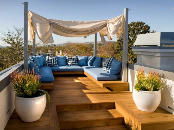 decoracion terrazas en tonos claros, muebles en azul celeste, cojines decorativos con motivos geométricos, grandes maceteros blancos con plantas verdes