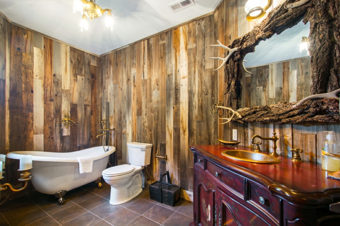 espacio decorado en estilo rústico, baños rusticos con paredes revestidas de madera y bañera vintage con patas garra, espejo original de madera