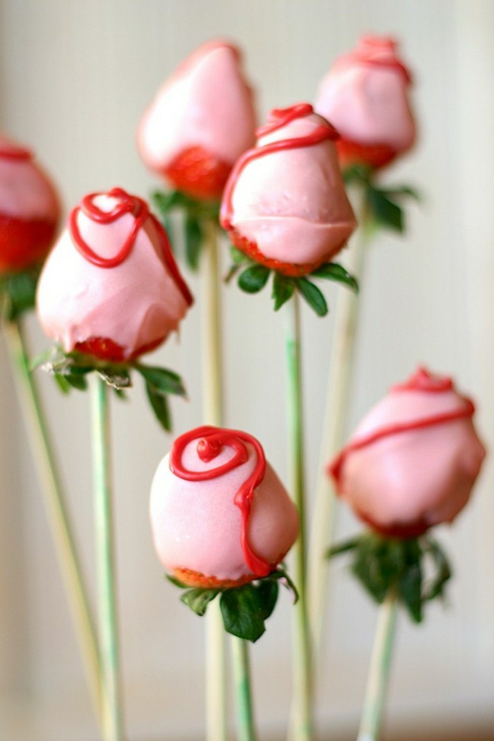 fresas en palillos de madera decoradas con crema y nata en color rosado, rosas decorativas que regalar a tu novio 