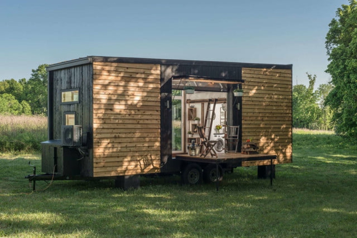mini casas, casa prefabricada de un diseño simple revestida de madera, terreno verde, pequeña plataforma de madera, 