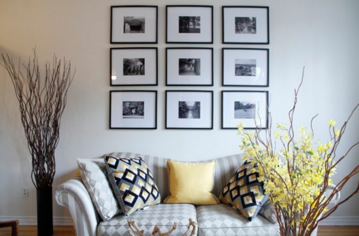 fotos originales, salón moderno con muebles tapizados con telas en motivos geométricos, pared en blanco decorada con cuadros en blanco y negro, plantas decorativas artificiales