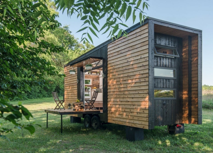 casas moviles, bonito ejemplo de casa prefabricada portatil colocada en un terreno verde, vivienda revestida de madera decorada de macetas colgantes 