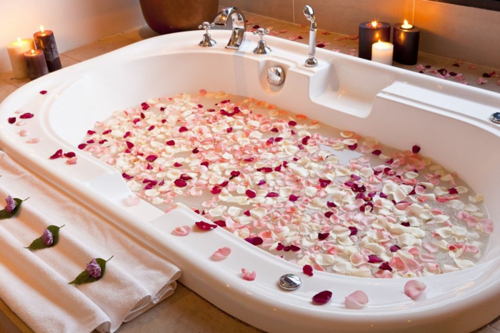 propuestas sobre como sorprender a tu pareja para el dia de los enamorados, bañera llena de hojas de rosas en blanco, rosado y rojo 