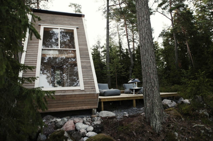 casas moviles, interesante idea de una cabaña en la montaña con grande ventanal y cubierta de madera, terreno con muchos árboles