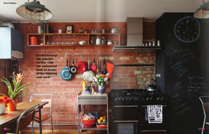 cocina moderna con elementos originales y muebles cocina en negro, pared de ladrillos y muchos objetos decorativos vintage