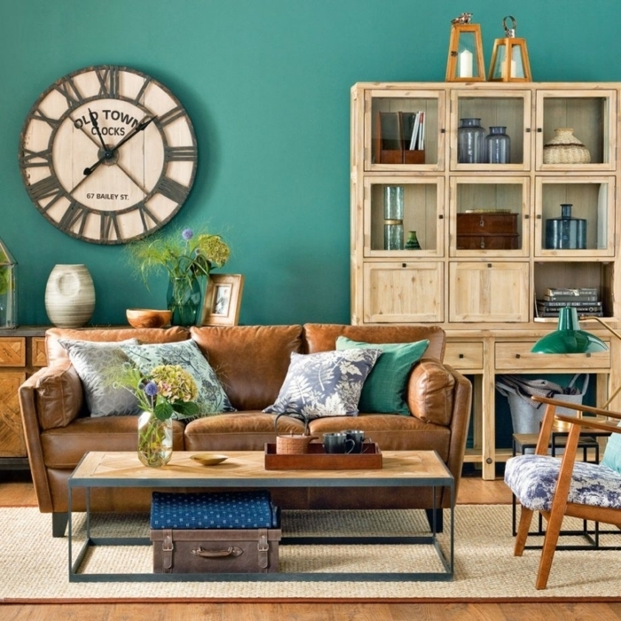 combinacion de colores, salón con encanto, alacena decorativa de madera, reloj de pared grande, pared color esmeralda, sofá de piel, elemntos vintage