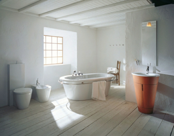 cuarto de baño grande decorado en blanco con bañera exenta y paredes en blanco, muebles de baño rusticos y suelo de madera 
