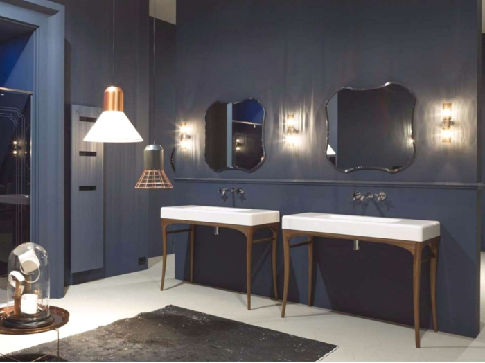 ideas de baño, muebles auxiliares de baño, madera. dos lavabos, espejos con forma irregular,paredes en azul oscuro, tapete, luz artificial