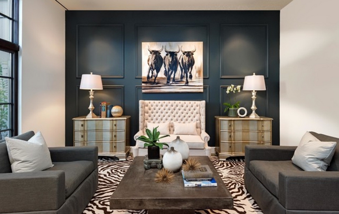 sala de estar con pared de acento en azul oscuro, cuadro grande con toros, mesa de madera, sillón tapizado en capitoné blanco, alfombra piel de zebra, ideas deoración, colores para paredes