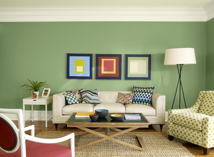 salón vintage, decoración en verde y blanco roto, cuadros geométricos, tapete de mimbre, techo bajo, sofá con cojines, colores para paredes,