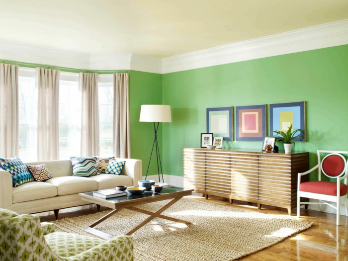salón con mucha luz natural, colores para paredes, paredes en verde, techo blanco roto, alfombra de mimbre, cuadros geométricos, sofá y mesa de café