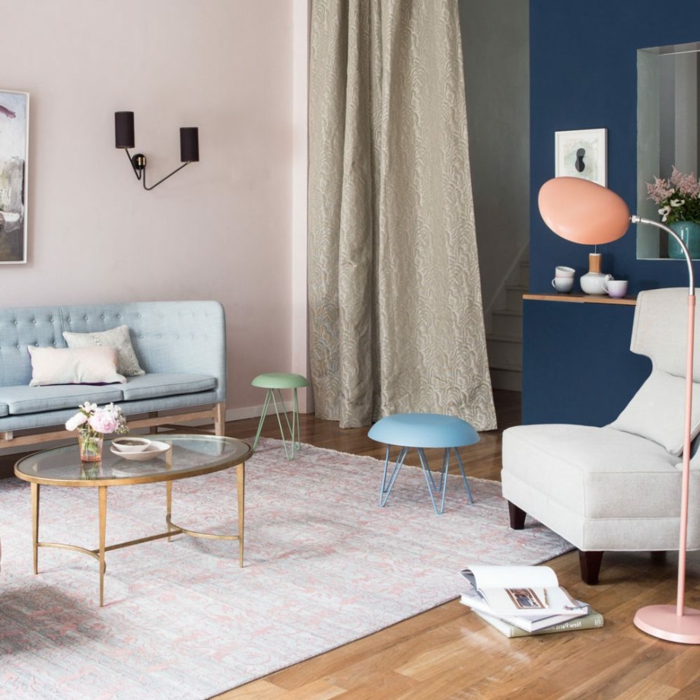 pinturas para salones, estilo escandinaco en colores pastel, pared en rosado, sofá azul celeste, suelo con aprquet, alfombra, mesa ovalada de vidrio
