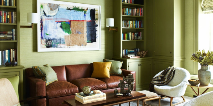 sala de estar estilo clásico, colores para salones, paredes con madera en color pistacho, sofá de piel, estanterías con libros, luz natural