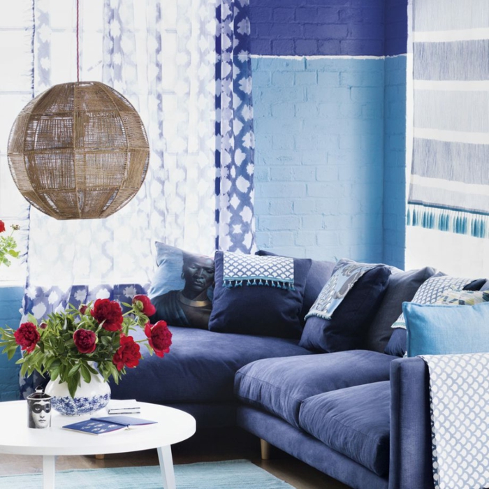 sala de estar, que colores se llevan para pintar un salon, pared con ladrillo vito en azul celeste y azul marino, lámpara colgante original, mesa redonda blanca con rosas rojas