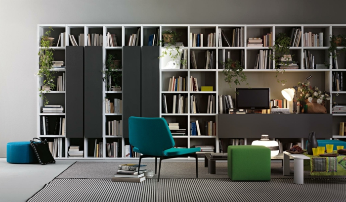 salón moderno, librería de madera blanca, decoración en blanco, negro y gris, silla azul, librerias, alfombra rayada, mesilla de café baja