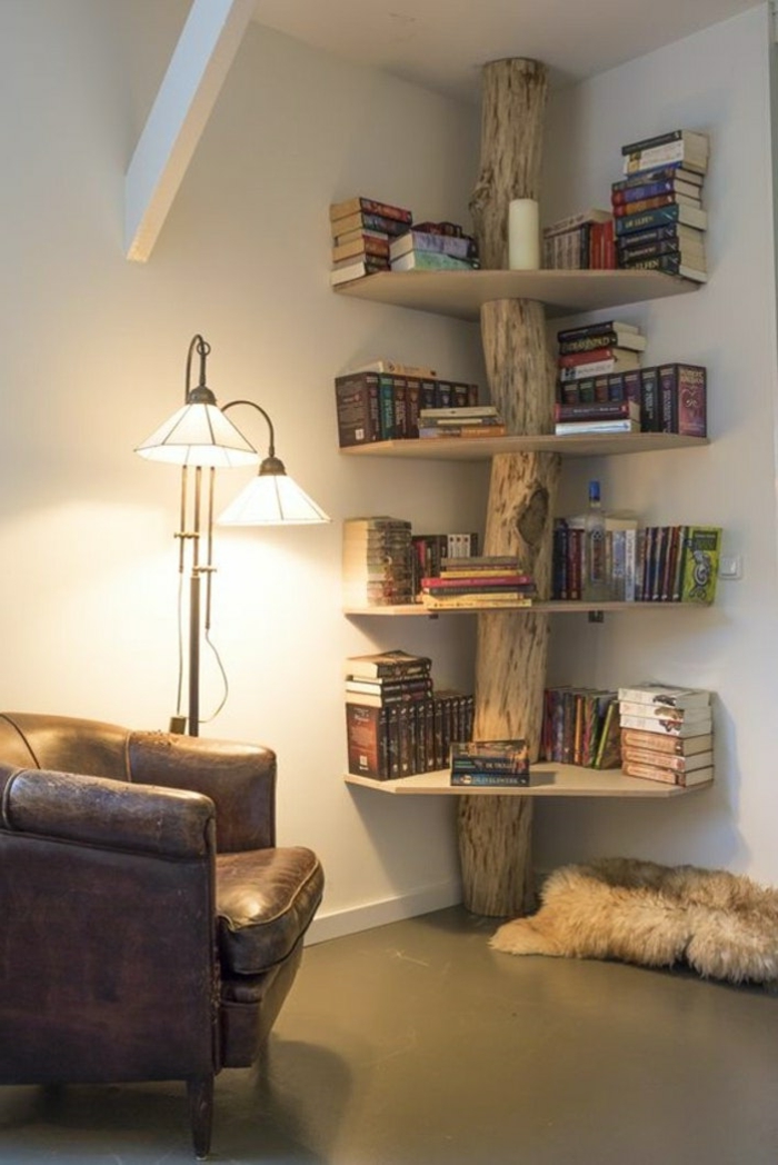 estantería original en forma de árbol con tronco natural, sillón tapizado de piel, lámpara blanca de metl, paredes blancas, librerías