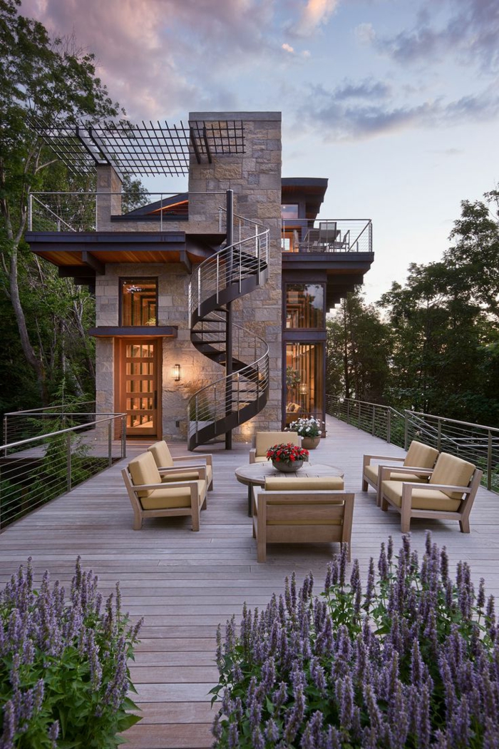 escaleras, patio grande con mesa y sillones, casa rústica grande con balcones, escalera de caracol exterior metálica con barandilla