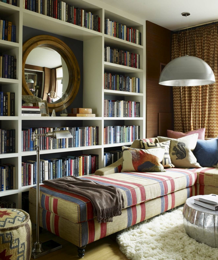 ideas de decoración, librerías, rincón de lectura, estantería de madera blanca, espejo redondo con marco de madera, sofá cama con cojines, tapete redondo peludo blanco