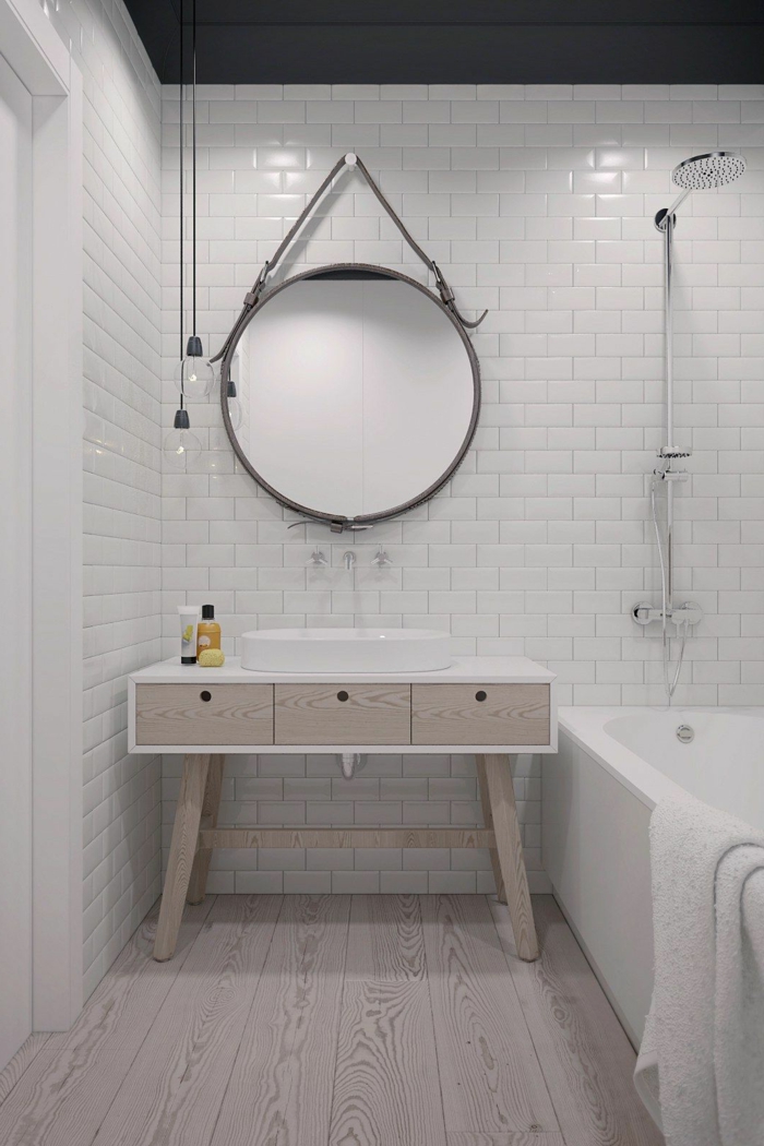 decoración minimalista, pared de ladrillo visto blanco, bañera, muebles auxiliares de baño, cajones de madera, espejo grande redondo