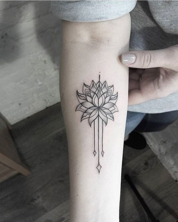 tatuaje flor de loto, tatuaje en blanco y negro, antebrazo mujer, flor de loto abierta con tres flechas