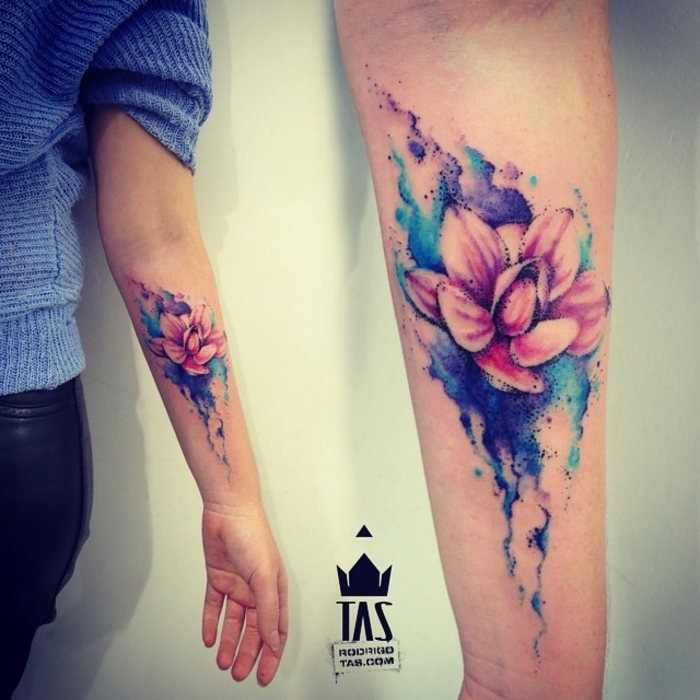 tatuaje flor de loto, tatuaje de acuarela en azul, morado y rosado, antebrazo mujer, flor de loto medio abierta
