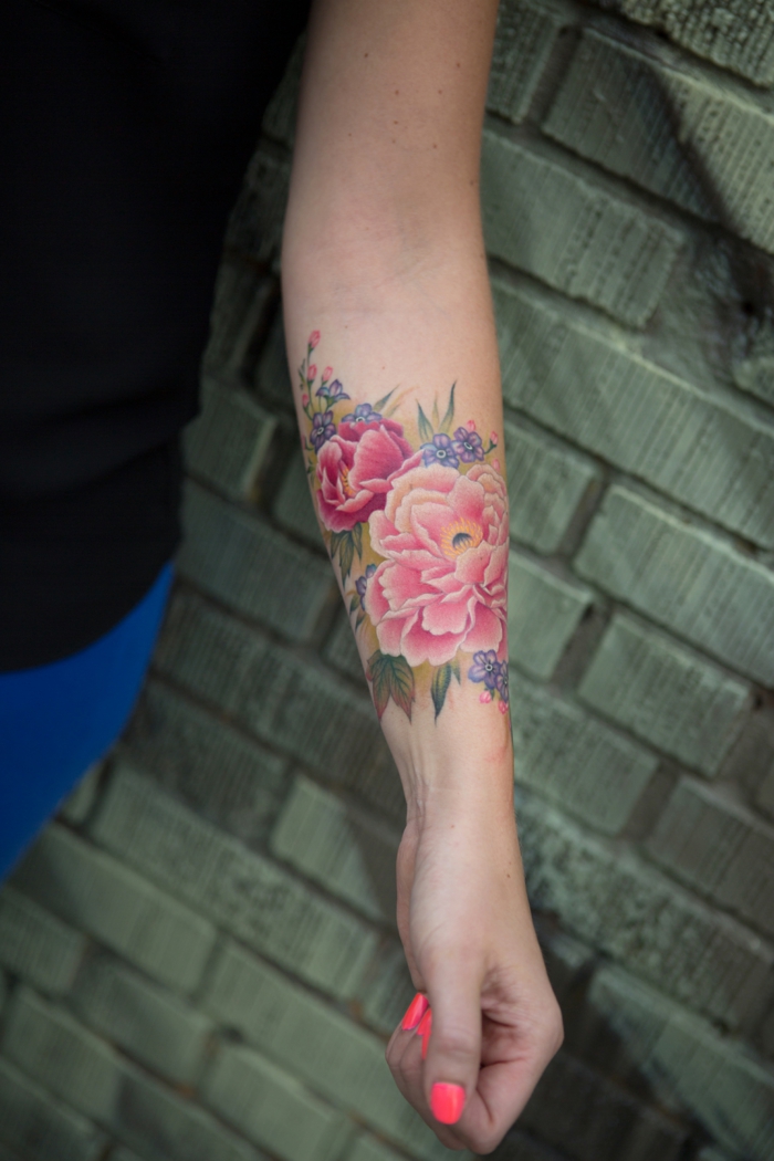 tatuajes de flores, mujer con esmalte en las uñas, tatuaje grande en el antebrazo, crisantemos en rosado con hojas verdes