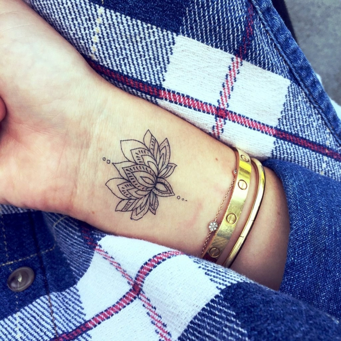 tatuajes de flores, tatuaje pequeño en la muñeca, flor de loto abierta en blanco y negro, mano de mujer con pulseras