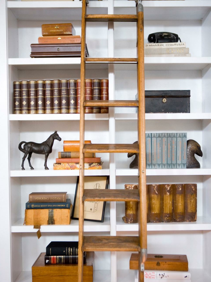 decoración con librería de madera blanca, libros antiguos, estatua de caballo, escalera de madera de mano, estanterias originales, 