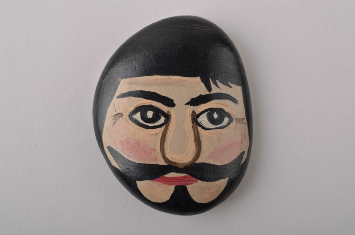 pintar con acrilico, piedra pintada a mano, cara de hombre con pelo negro, barba y bigotes, pintura acrilica
