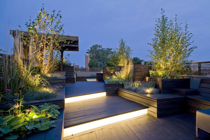 terraza nivelada con lámparas empotradas, pergola de madera grande, terrazas modernas con muchas plantas decorativas 