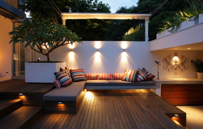 diseño de terrazas modernas decoradas en estilo contemporáneo, suelo de madera, grande macetero con planta verde y lámparas empotradas