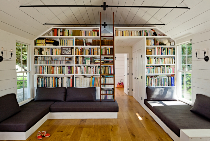 estanteria escalera, salón grande, biblioteca de suelo a techo, madera blanca, escalera desplazable, techo triangular con tarima blanca, interior rústico