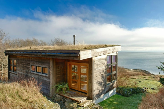 mini casas de ensueño, casa en la orilla del mar con diseño simple y forma cuadrada, muchas ventanas de diferente tamaño y forma